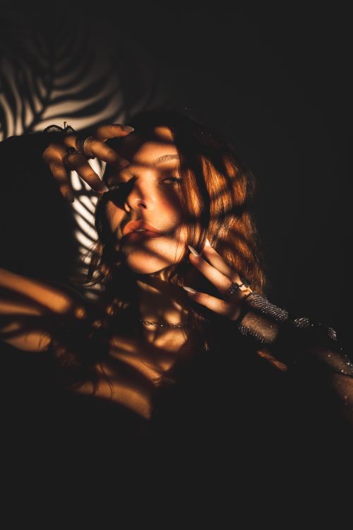 Free Artistic portrait of a woman with intricate shadows creating a dramatic effect. Stock Photo