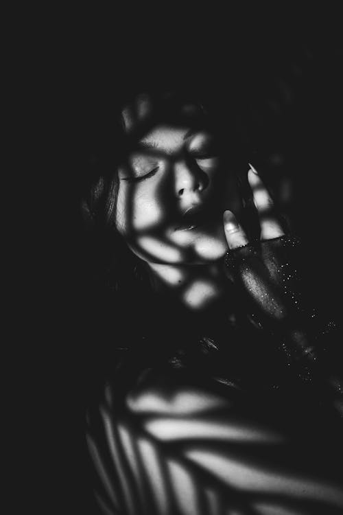 Grayscale Photo of Woman With Shadows on Face 