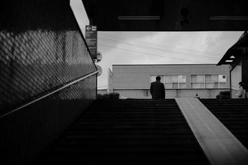 Free Grayscale Photo of Man Near Stairs in Low Angle Shot  Stock Photo