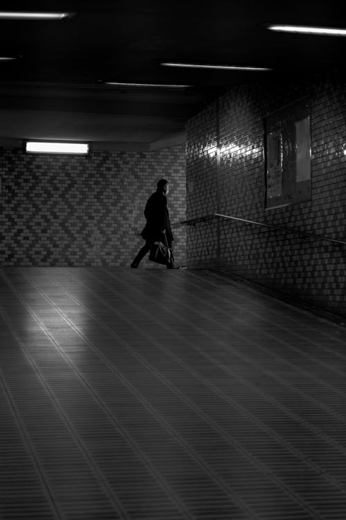 Free Grayscale Photo of Man Walking on Hallway  Stock Photo