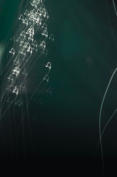 Dynamic abstract light trails forming heart shapes on a dark green background.