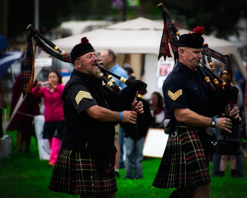 Two Men Playing Wind Instruments on Ground