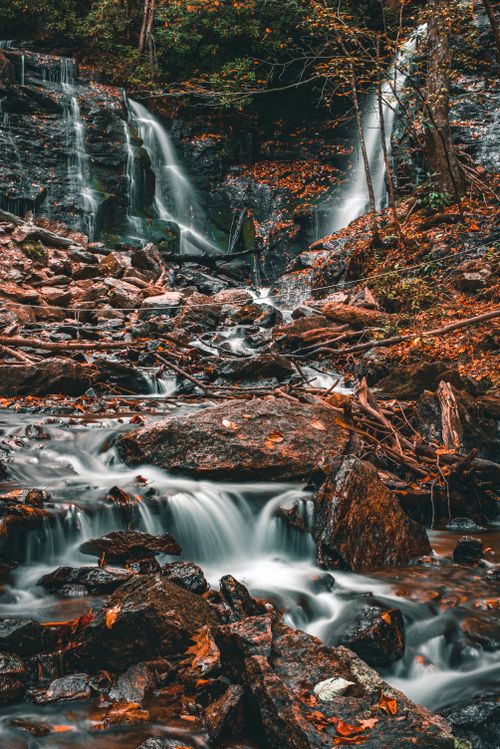 Free Peaceful waterfall cascades through a rocky forest in autumn, showcasing nature's beauty. Stock Photo
