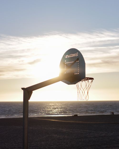 Free Silhouette of a basketball hoop against a sunset beach in Cádiz, Spain. Stock Photo