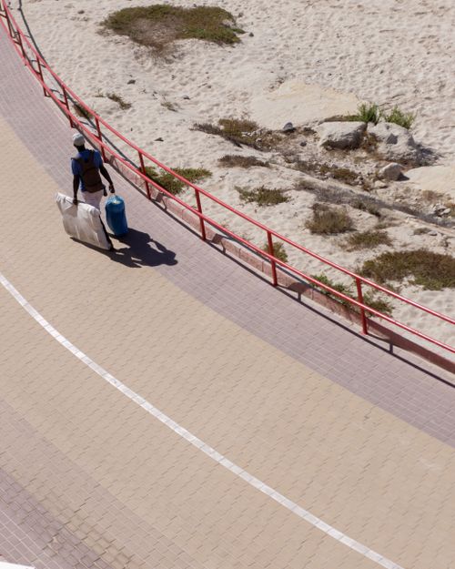 Free A street vendor walks along a seaside walkway in Cádiz, Spain, carrying goods for sale. Stock Photo