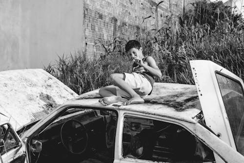 A Boy Sitting on Top of the Car