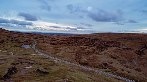 Stunning aerial view of the Brecon Beacons, Wales at sunrise with rolling hills and a curving road.