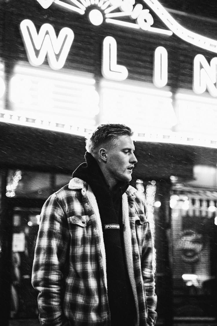 Man In Casual Clothing Standing In Front Of An Illuminated Facade 