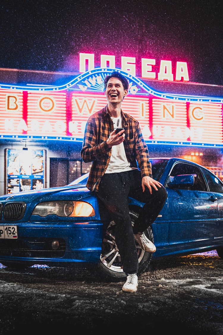 Man Sitting On Blue Car