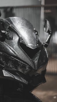 Detailed close-up of a motorcycle's front with raindrops, showcasing sleek design under low light.