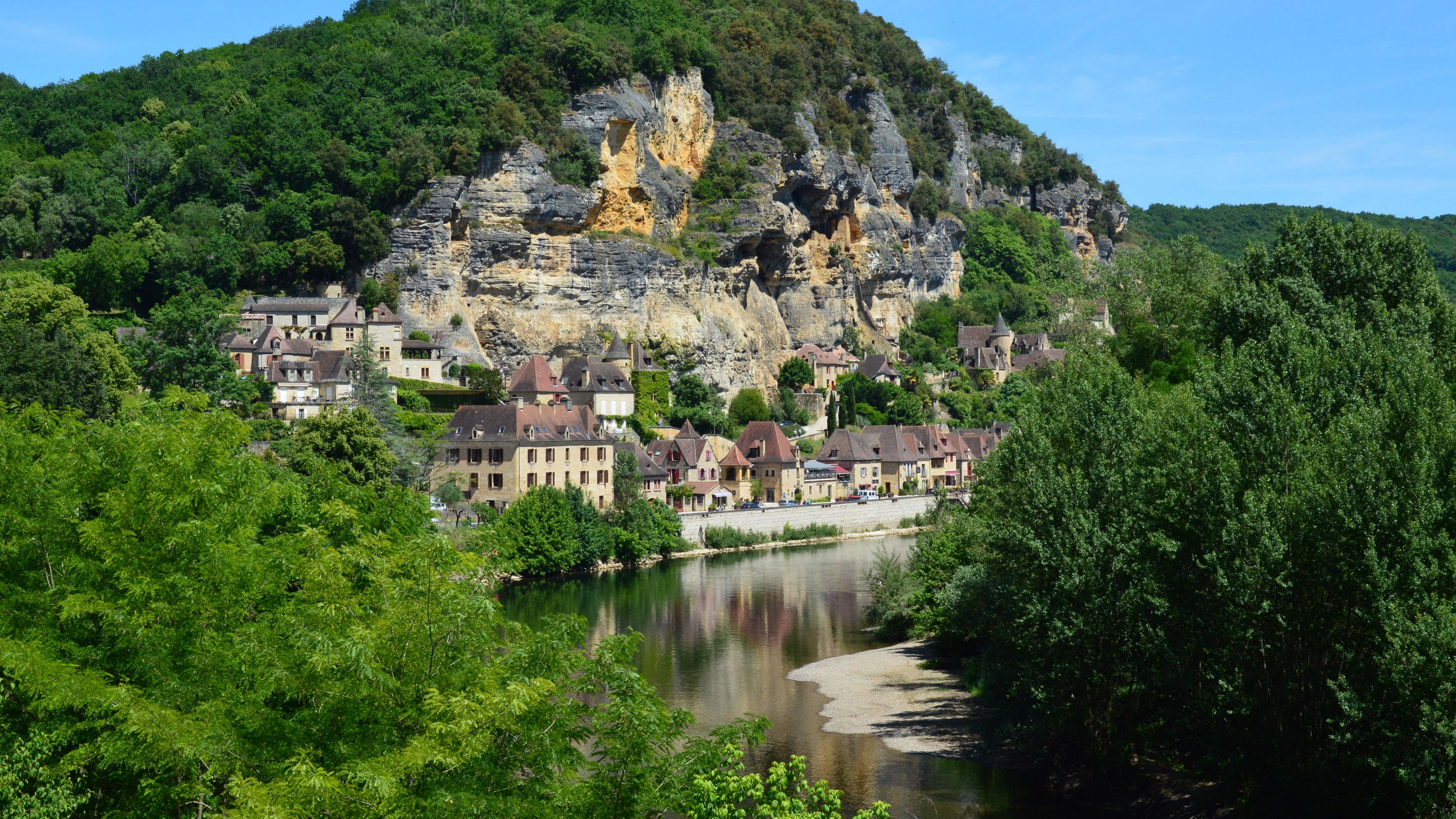 Picturesque village nestled by a river under dramatic rocky cliffs. Picturesque village nestled by a river under dramatic rocky cliffs.