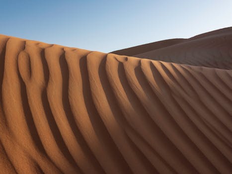 Explore the mesmerizing patterns of Ras Al-Khaimah's stunning sand dunes at sunrise.
