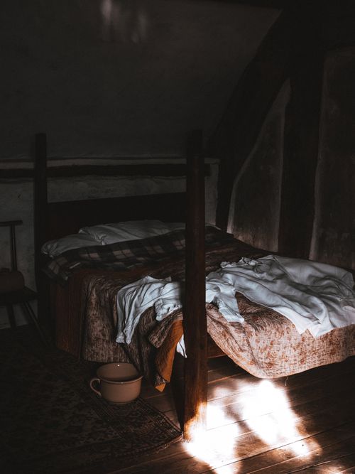 Free Vintage bedroom with wooden floor and sunlight streaming in, creating a warm atmosphere. Stock Photo