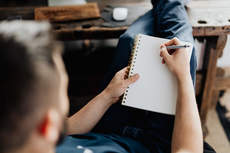 Man Lying Writing In Notebook