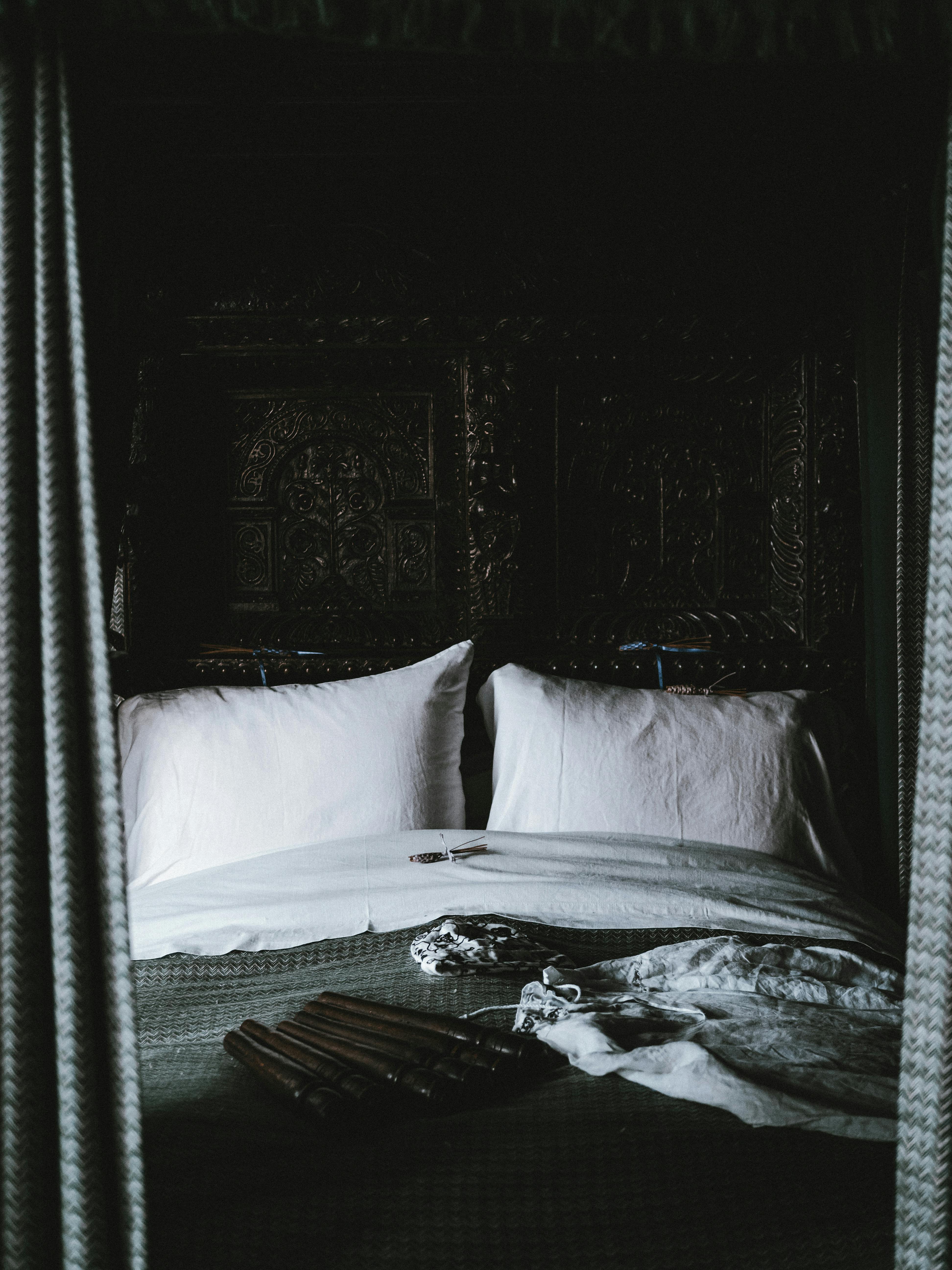 Elegant bedroom featuring vintage decor with white pillows and an ornate headboard, evoking a classic and retro feel.