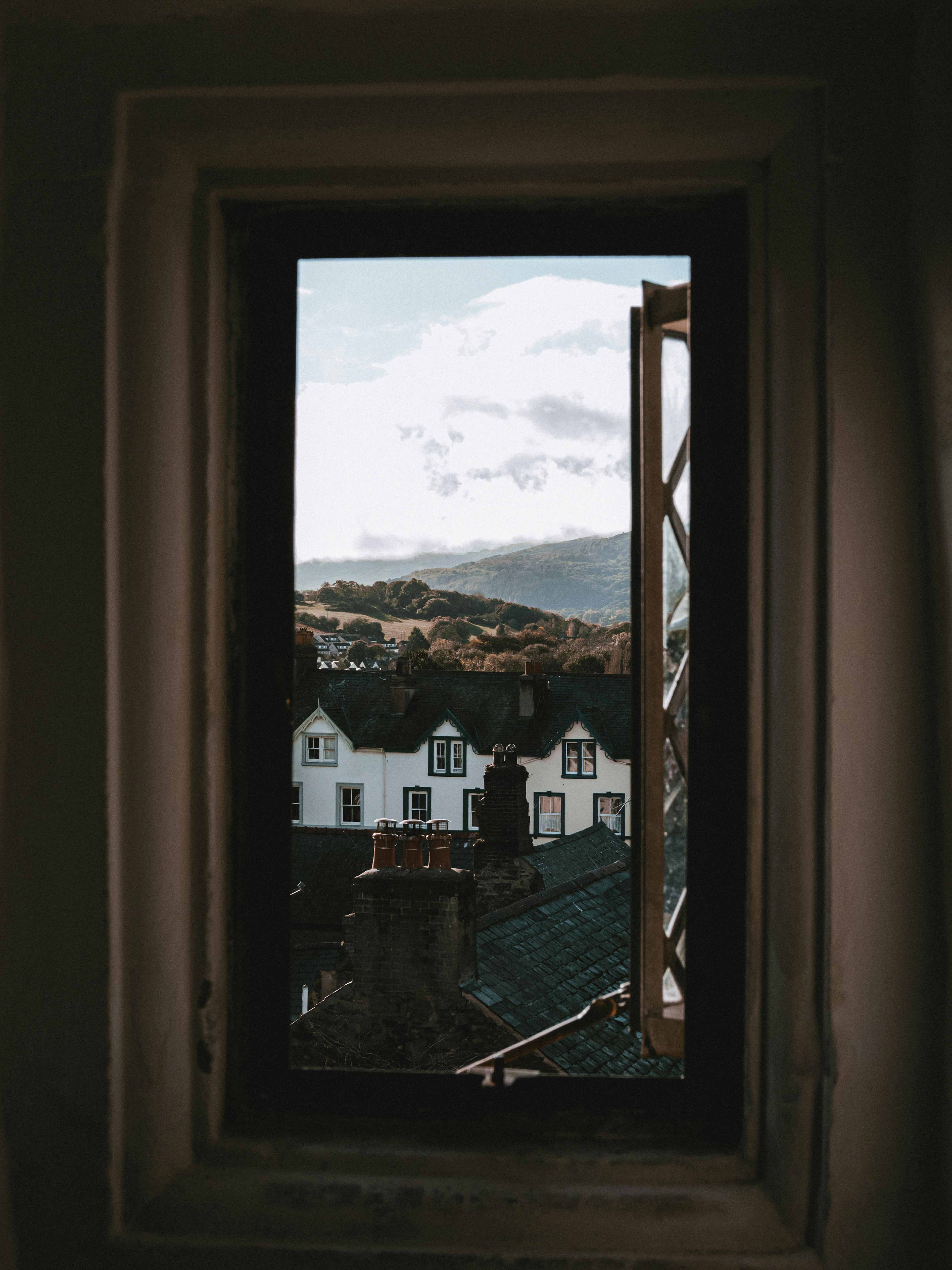 Charming view of Conwy's rooftops and countryside through a window, capturing the essence of Welsh architecture.