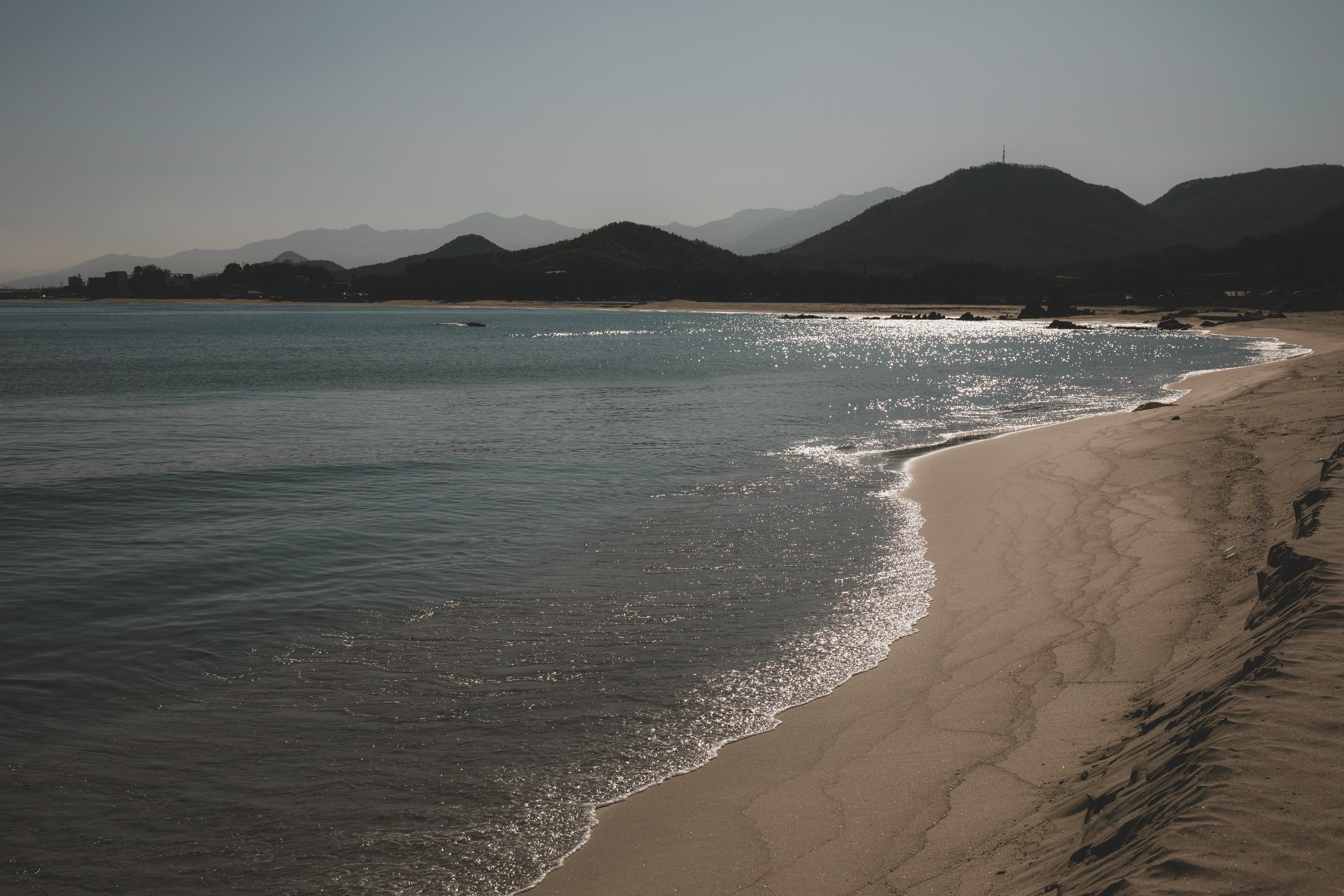 Peaceful beach with mountains in Goseong-gun, South Korea, shines under sunlight.