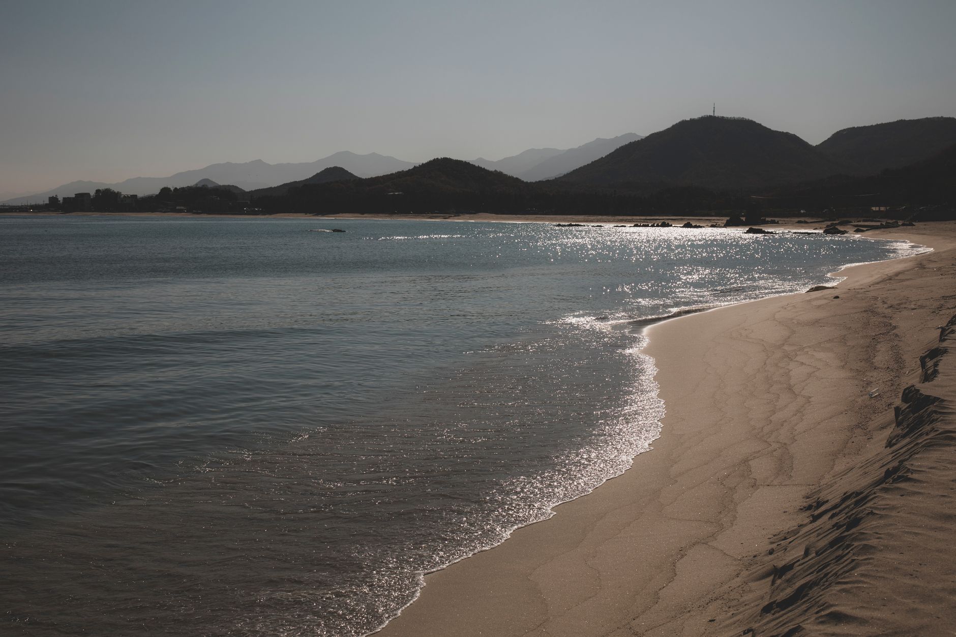 Peaceful beach with mountains in Goseong-gun, South Korea, shines under sunlight.