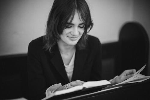A Grayscale of a Woman in a Blazer Reading a Book