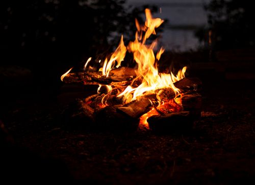 Free A serene bonfire outdoors at night with logs burning and vivid flames illuminating the scene. Stock Photo