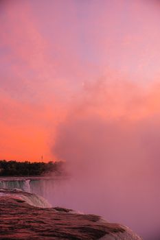 Beautiful sunset view over Niagara Falls with vibrant colors and mist.