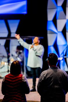 Back view of an audience watching a dynamic stage performance in vibrant lighting.