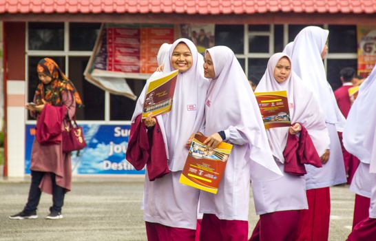 Woman in White Hijab Holding Yellow and Red Labeled Box
