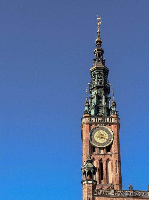 Free Vertical shot of Gdańsk Main Town Hall's tower with clock against a clear blue sky. Stock Photo