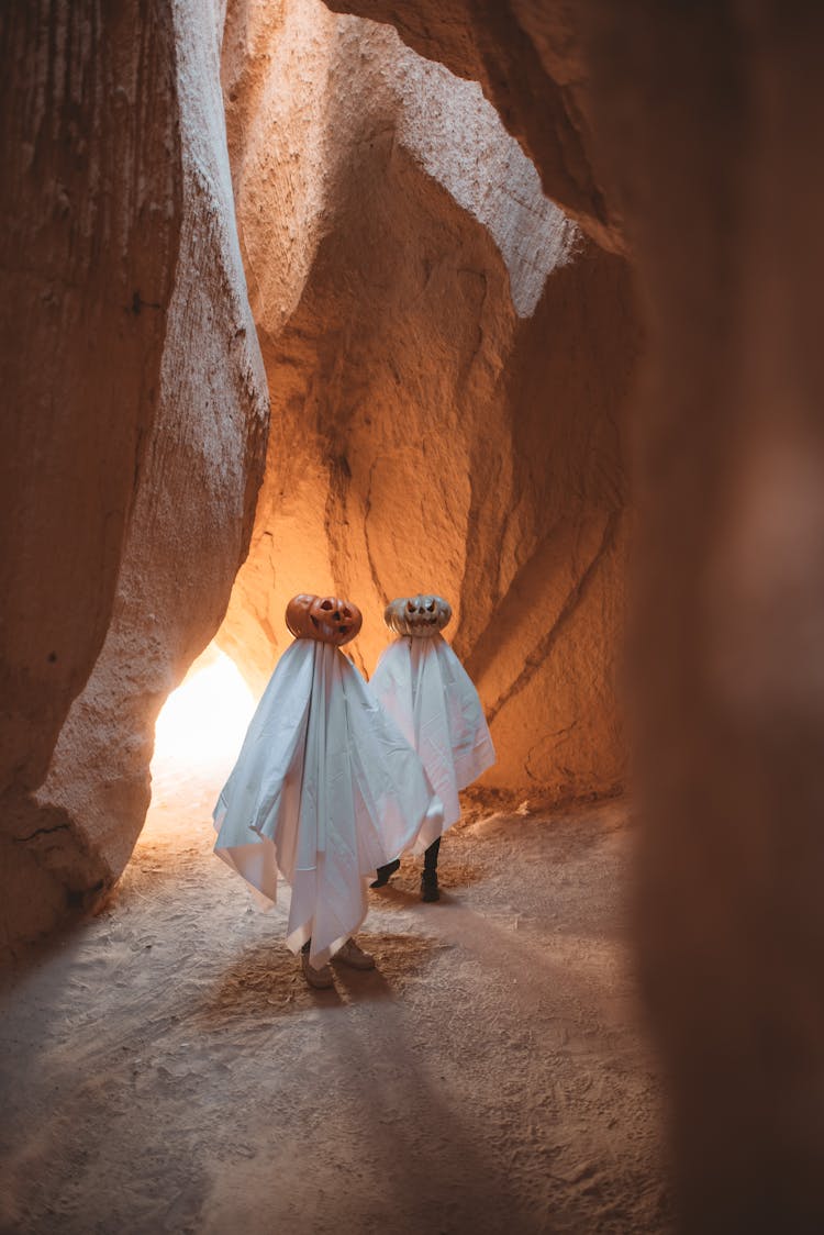 Couple Wearing Pumpkin Heads Standing In Cave