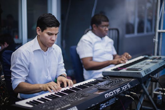 Two musicians focused on playing keyboards in a music studio setting.