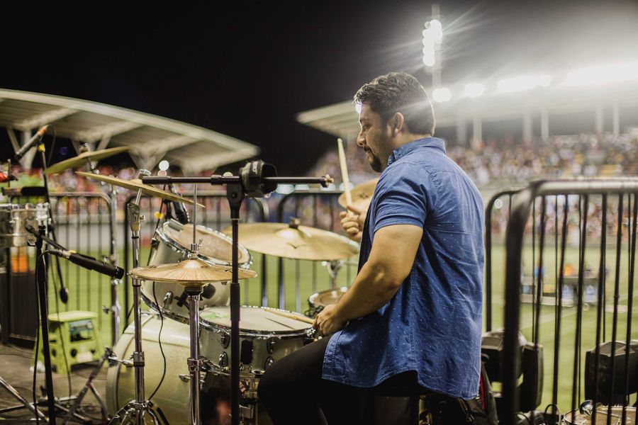 A drummer playing a kit under stage lights — photo by Luis Quintero on Pexels