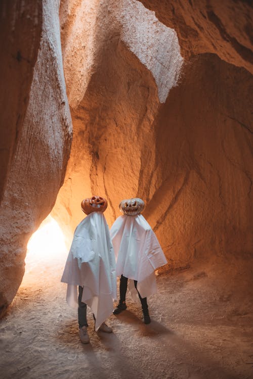 People Covered in White Sheets in a Cave