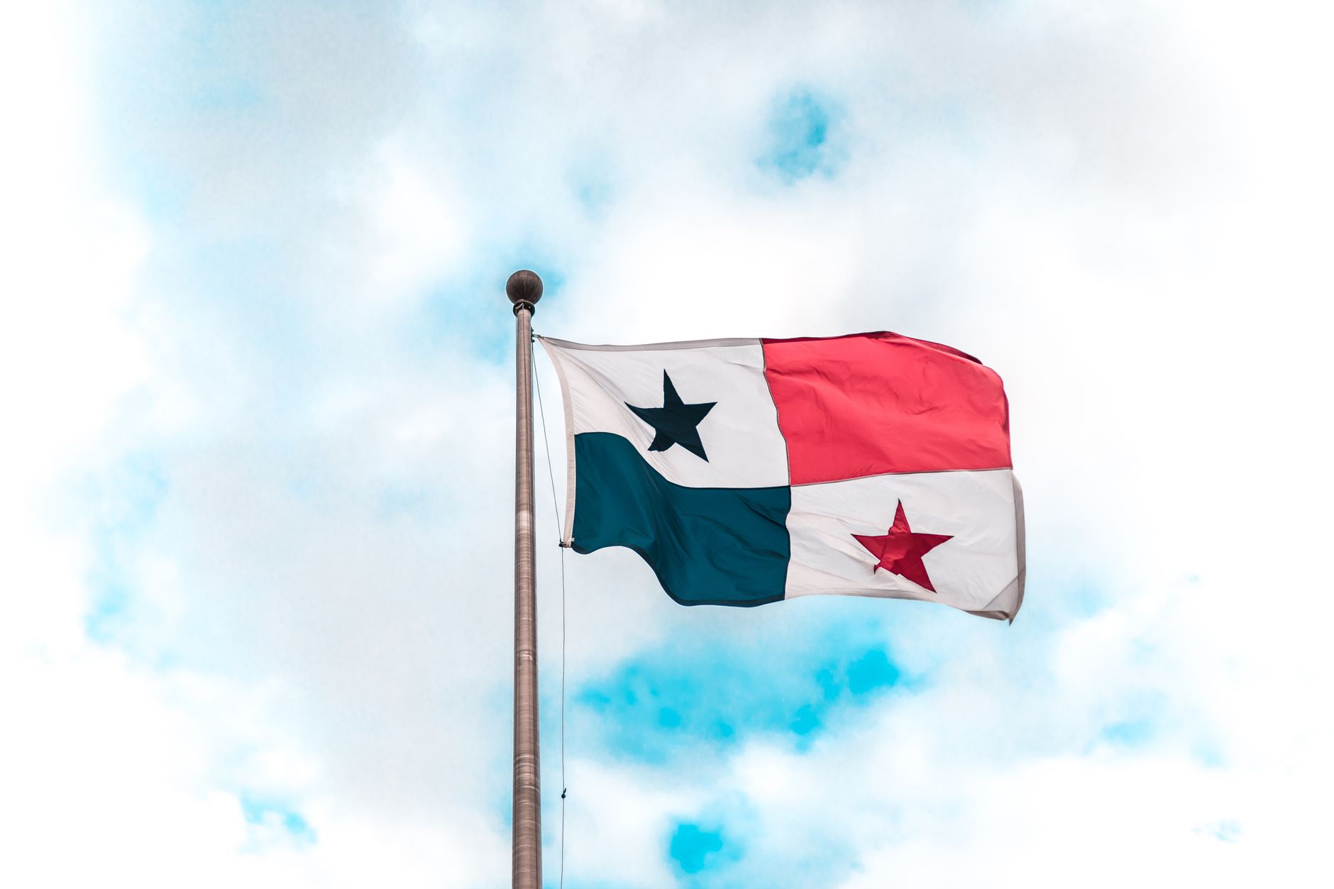Panama national flag waving on a flagpole against a bright blue sky.