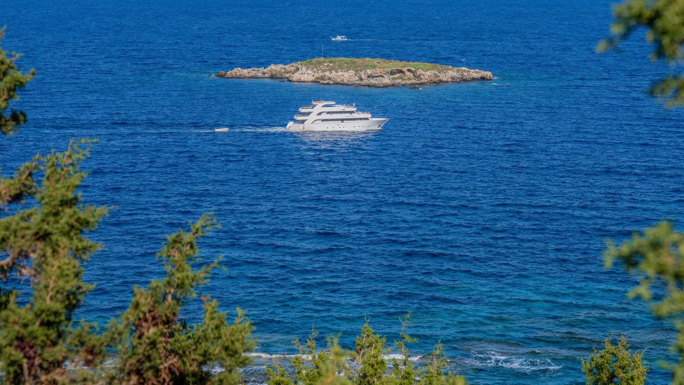 Yacht cruising past a small island in blue water