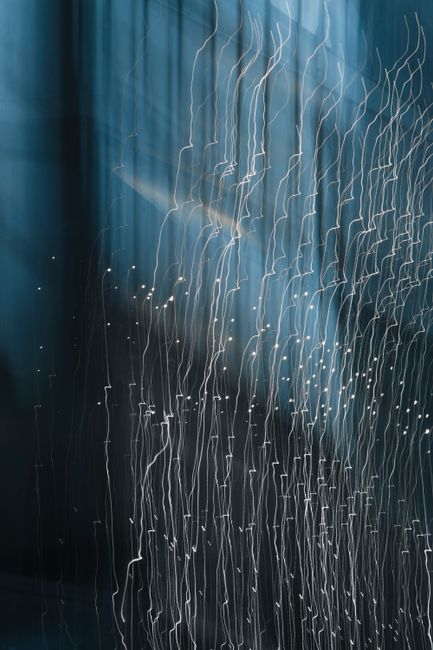 Intriguing abstract photograph capturing dynamic lines of light in vertical motion against a dark background.