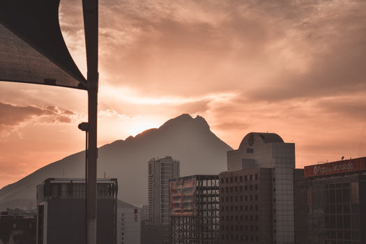 Captivating sunset over Monterrey's skyline with Cerro de la Silla silhouette, offering a serene urban scene.
