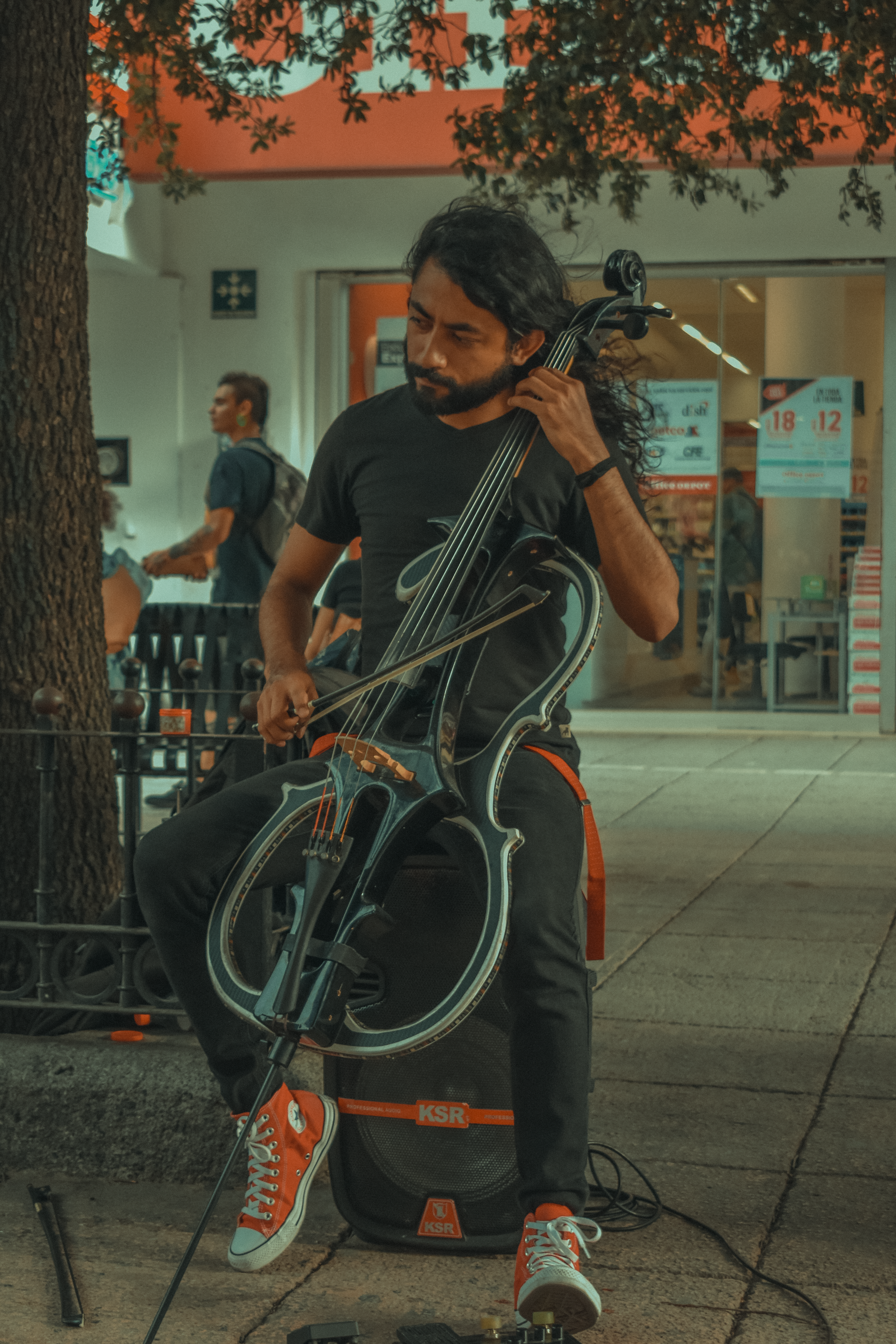 Street performer playing the cello on a busy city street in Monterrey, Mexico. Captivating musical street art.