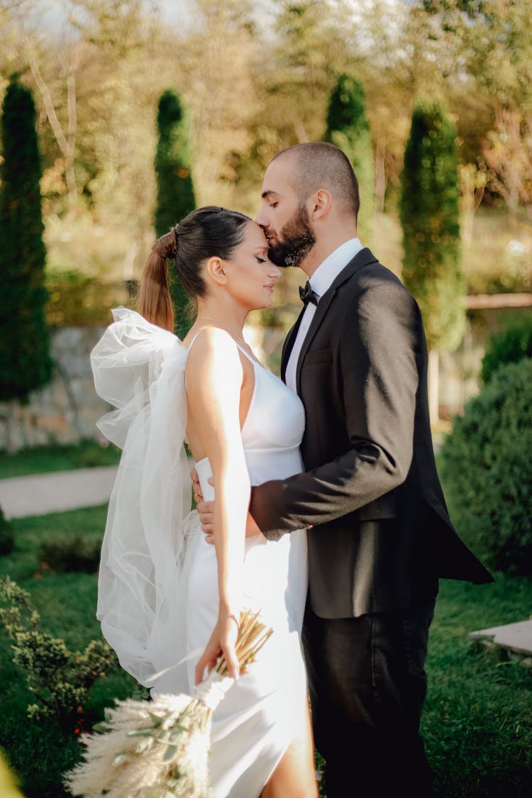 Groom Kissing Bride In Park