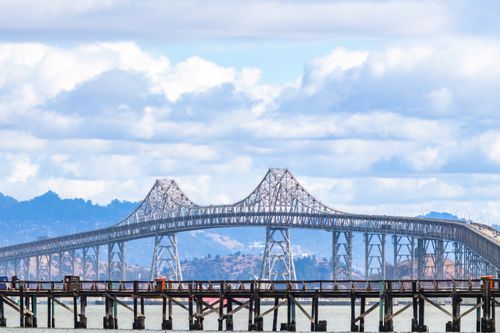 Free Stunning view of the San Francisco Bay Bridge with a backdrop of fluffy clouds. Stock Photo