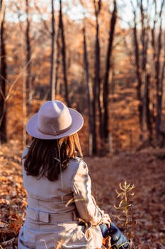 A fashionable woman in a beige coat enjoying the autumn woods.