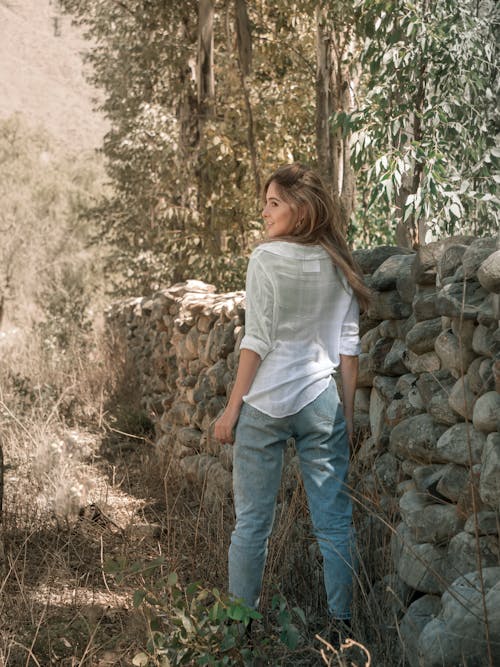 Blonde Woman in White Shirt and Jeans Posing by Fence