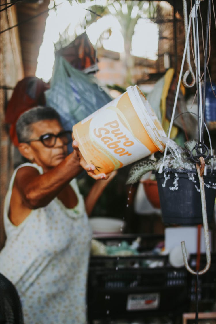 Woman Pouring Water From Bucket At The Market