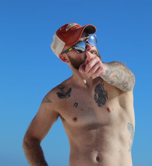A Tattooed Topless Man Pointing His Finger