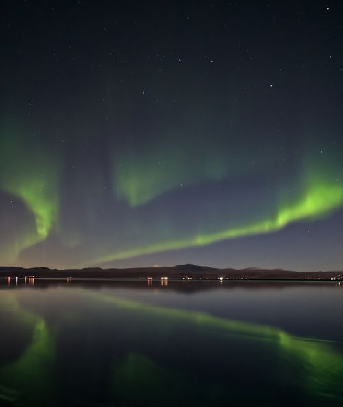 Free Stunning display of Northern Lights reflecting over a tranquil lake in Ölfus, Iceland at night. Stock Photo