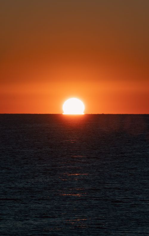 Free Captured at golden hour, the sun sets dramatically over the ocean, creating a stunning horizon view. Stock Photo
