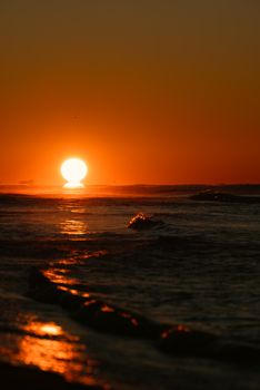 Vibrant sunset over the ocean with reflective waves creating a serene seascape.