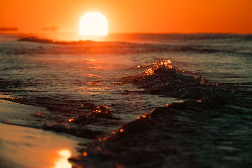 Free Captivating sunset with ocean waves glistening under golden skies, offering a serene coastal view. Stock Photo