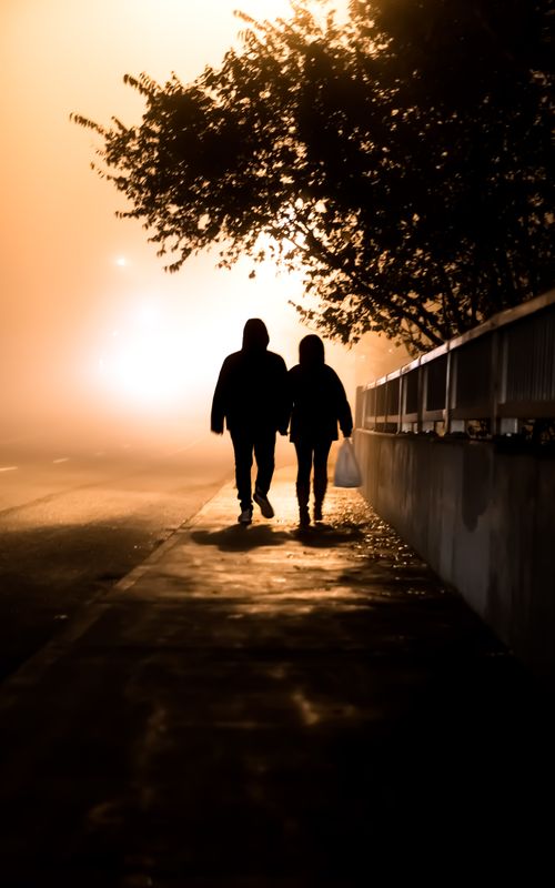 Free A silhouette of a couple holding hands, walking on a foggy night in Toronto, Canada. Stock Photo