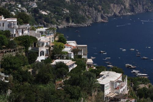 Free Picturesque view of Italian village on cliffs overlooking the sea, lush greenery and boats. Stock Photo