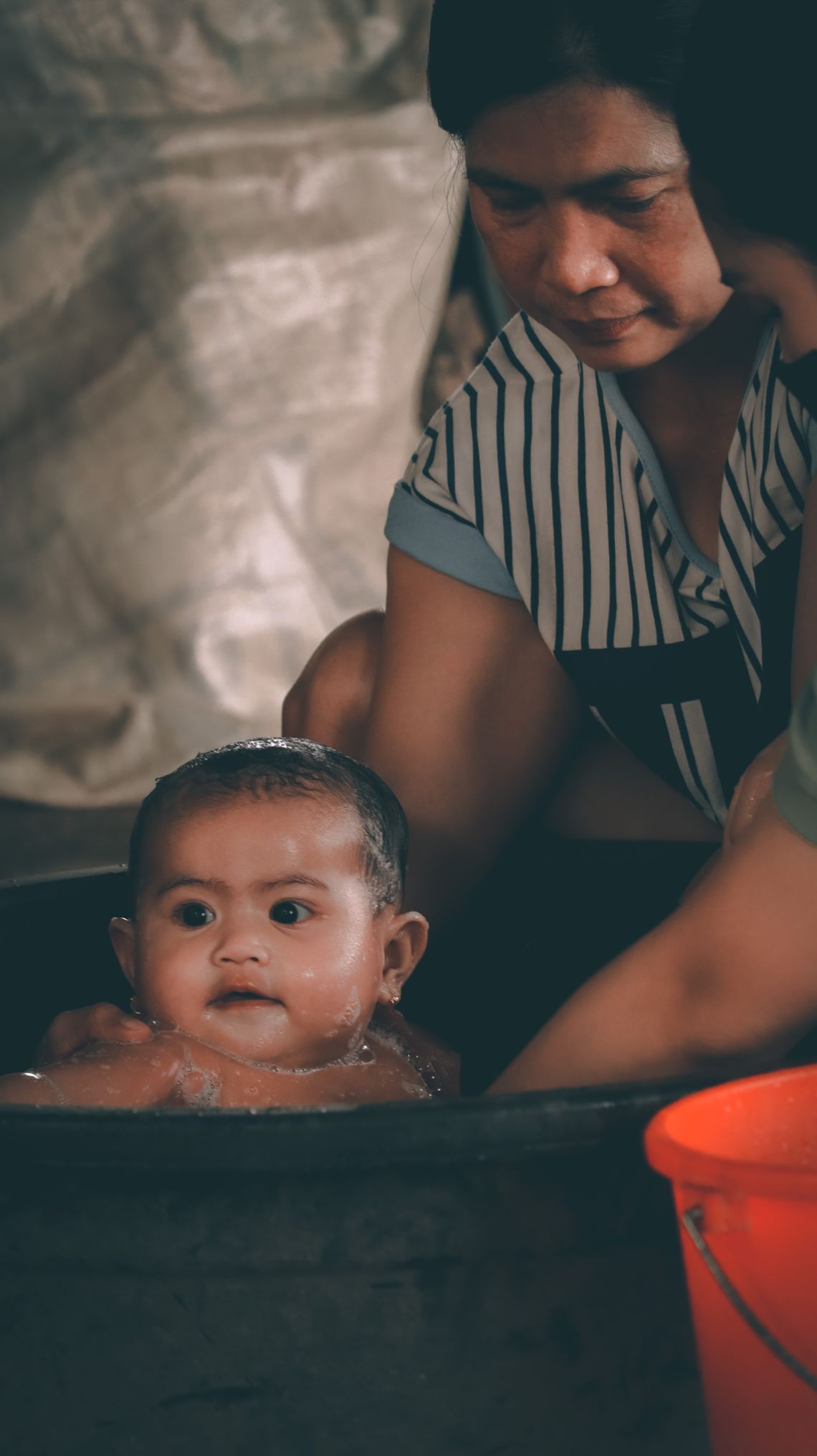 Mother gently bathing her baby in a warm home setting